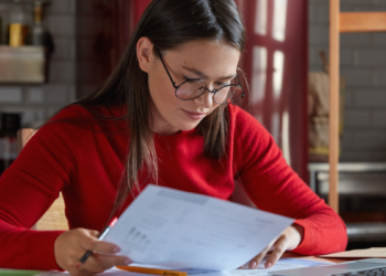 Pessoa estudando e analisando documentos para representar preparação para concursos públicos.