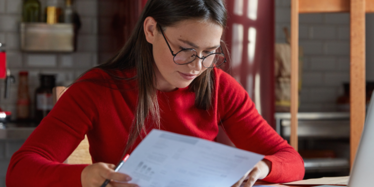 Pessoa estudando e analisando documentos para representar preparação para concursos públicos.
