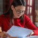 Pessoa estudando e analisando documentos para representar preparação para concursos públicos.