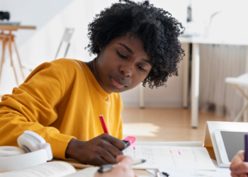 Jovem estuda com caderno e materiais de apoio, em referência a concursos com editais recém-publicados.