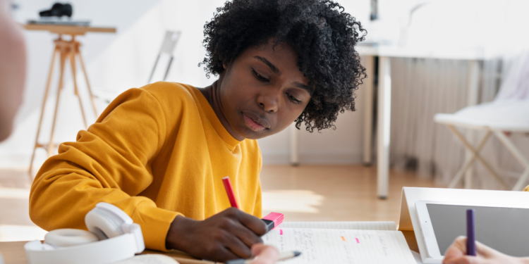 Jovem estuda com caderno e materiais de apoio, em referência a concursos com editais recém-publicados.