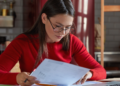 Mulher analisa documentos durante preparação para concursos públicos com inscrições abertas em diferentes estados.