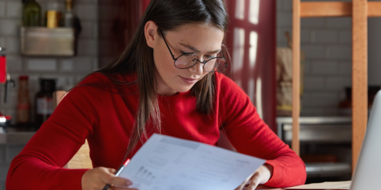 Mulher analisa documentos durante preparação para concursos públicos com inscrições abertas em diferentes estados.