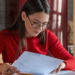 Mulher analisa documentos durante preparação para concursos públicos com inscrições abertas em diferentes estados.