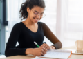 Estudante estudando em mesa com caderno e caneta, representando preparação para concursos públicos com inscrições abertas.