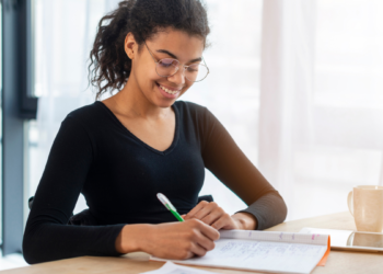 Estudante estudando em mesa com caderno e caneta, representando preparação para concursos públicos com inscrições abertas.