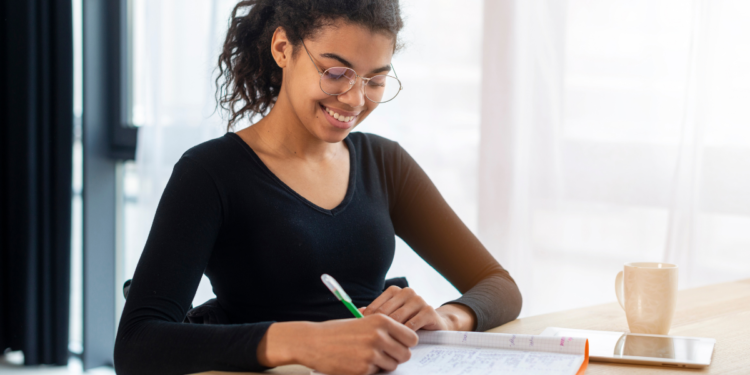 Estudante estudando em mesa com caderno e caneta, representando preparação para concursos públicos com inscrições abertas.