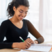 Estudante estudando em mesa com caderno e caneta, representando preparação para concursos públicos com inscrições abertas.