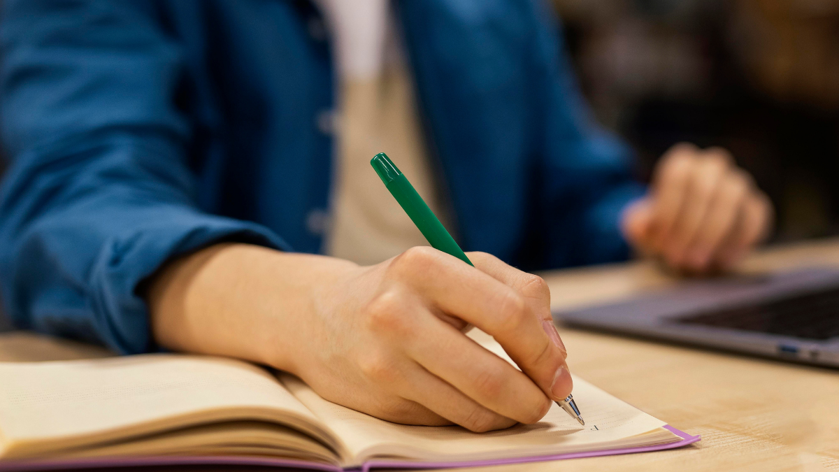 Pessoa estudando para concursos públicos com material de preparação sobre a mesa.