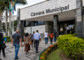 Pessoas caminham em direção a uma Câmara Municipal, em referência aos concursos públicos com vagas em SC, TO e RO.