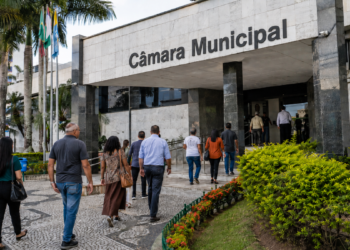 Pessoas caminham em direção a uma Câmara Municipal, em referência aos concursos públicos com vagas em SC, TO e RO.