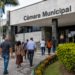 Pessoas caminham em direção a uma Câmara Municipal, em referência aos concursos públicos com vagas em SC, TO e RO.