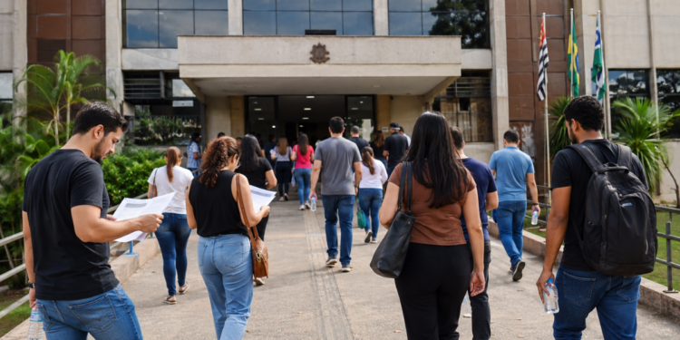 Pessoas se dirigindo a prédio público para representar concursos das Câmaras Municipais com inscrições abertas.