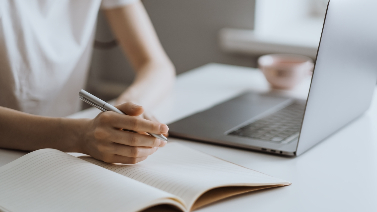 Pessoa estudando com caderno e notebook em preparação para concursos públicos e processos seletivos.