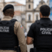 Policiais militar e civil da Bahia vistos de costas em uma área urbana.
