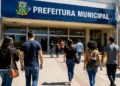 Pessoas caminham em direção à prefeitura, representando concursos públicos com inscrições abertas na Bahia, Maranhão e Paraná.
