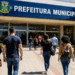 Pessoas caminham em direção à prefeitura, representando concursos públicos com inscrições abertas na Bahia, Maranhão e Paraná.