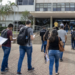 Candidatos caminham para prédio público com documentos de concursos de prefeituras.