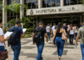 Candidatos caminham em direção a uma prefeitura durante seleção para concurso público.