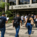 Candidatos caminham em direção a uma prefeitura durante seleção para concurso público.