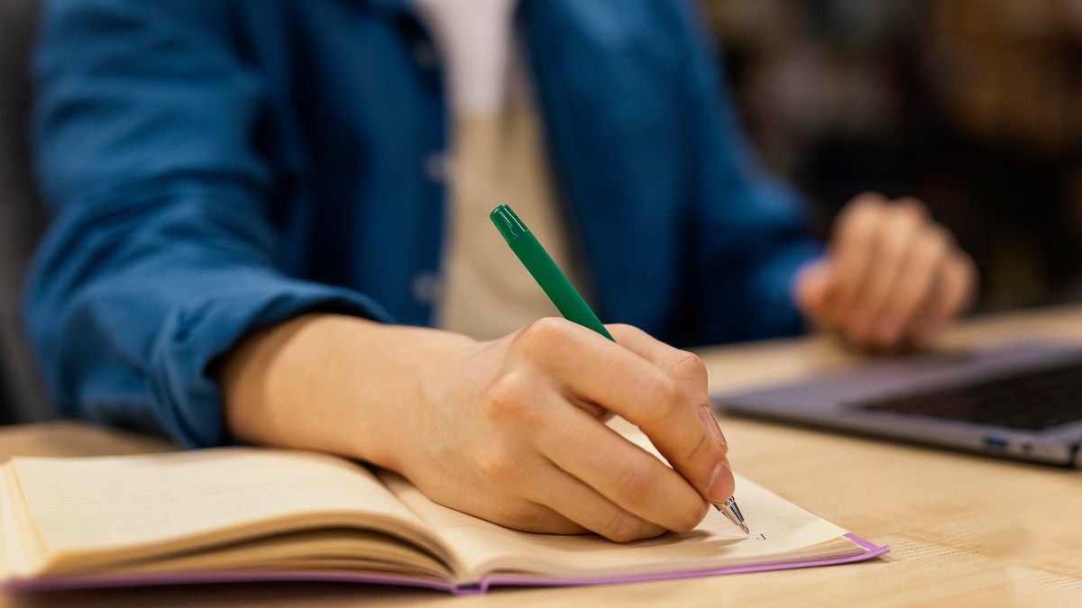 Pessoa estudando para concursos públicos com caderno e materiais de preparação.