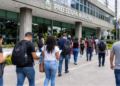 Candidatos caminham em direção à prefeitura municipal com documentos de concurso público para inscrições e provas em São Paulo.