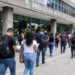 Candidatos caminham em direção à prefeitura municipal com documentos de concurso público para inscrições e provas em São Paulo.