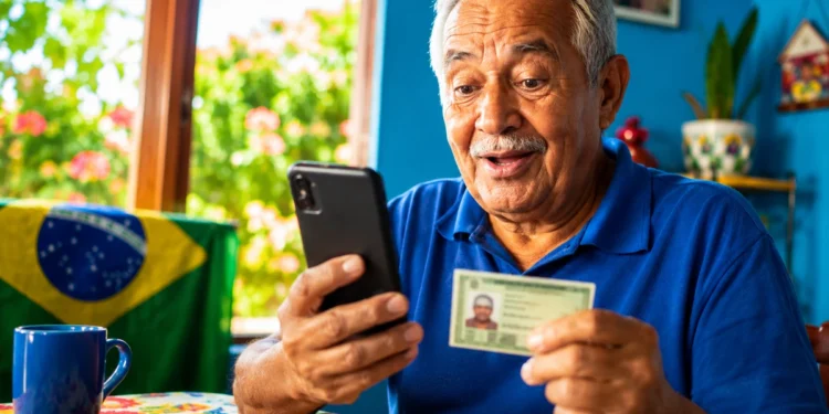 Aposentado consulta celular enquanto segura documento, em referência ao consignado do INSS, sem biometria facial