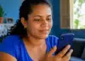 Mulher consulta pelo celular as informações da parcela de agosto do Bolsa Família.