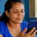 Mulher consulta pelo celular as informações da parcela de agosto do Bolsa Família.