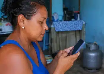 Mulher consulta pelo celular informações sobre o vale-recarga do programa Gás do Povo