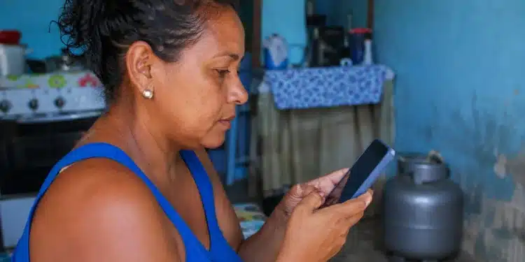 Mulher consulta pelo celular informações sobre o vale-recarga do programa Gás do Povo