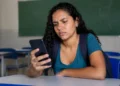 Estudante consulta informações sobre o pagamento do programa Pé-de-Meia pelo celular em sala de aula