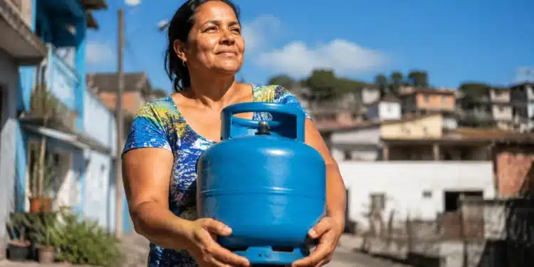 Mulher segura botijão de gás durante ação relacionada ao vale-recarga do Gás do Povo 2026
