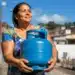 Mulher segura botijão de gás durante ação relacionada ao vale-recarga do Gás do Povo 2026