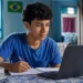 Estudante brasileiro estudando em casa com notebook e caderno para cursos gratuitos em 2026
