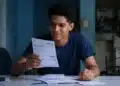 Estudante analisa documentos representando o desconto na dívida do Fies pelo Desenrola Adimplentes.