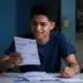 Estudante analisa documentos representando o desconto na dívida do Fies pelo Desenrola Adimplentes.
