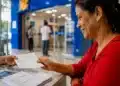 Mulher recebendo documentos durante atendimento bancário, representando o público apto à renegociação de dívidas pelo Desenrola Adimplentes.