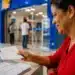 Mulher recebendo documentos durante atendimento bancário, representando o público apto à renegociação de dívidas pelo Desenrola Adimplentes.