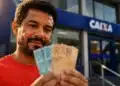 Trabalhador informal segura notas de real em frente a uma agência bancária, representando o acesso ao crédito pelo Desenrola Adimplentes.