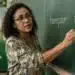 Professora de língua portuguesa em sala de aula com as palavras “tampar” e “tapar” escritas no quadro, destacando a diferença de significado entre os termos.