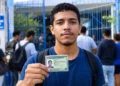 Jovem candidato segura documento de identificação na entrada de escola, representando os documentos exigidos para a aplicação do Encceja 2026.