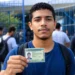 Jovem candidato segura documento de identificação na entrada de escola, representando os documentos exigidos para a aplicação do Encceja 2026.