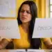 Jovem compara as palavras “obsecado” e “obcecado” escritas em folhas de papel, representando a dúvida sobre a grafia correta.