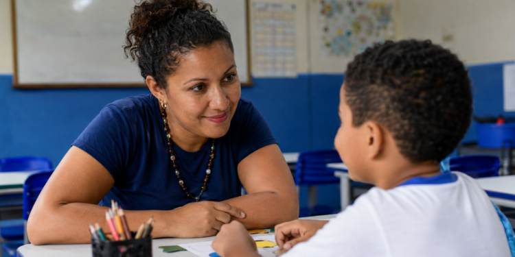 Professora acompanha criança em atividade educativa relacionada à inclusão e ao desenvolvimento.