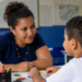 Professora acompanha criança em atividade educativa relacionada à inclusão e ao desenvolvimento.