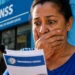Mulher lê documento em frente a uma agência do INSS após o encerramento definitivo do Meu INSS Vale+.
