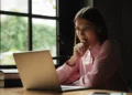 Mulher consulta informações em notebook sobre possíveis fraudes em concursos públicos.
