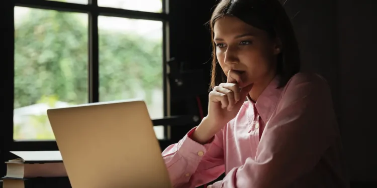 Mulher consulta informações em notebook sobre possíveis fraudes em concursos públicos.